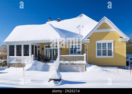 Rear of yellow with white trim cottage style house in winter. Stock Photo