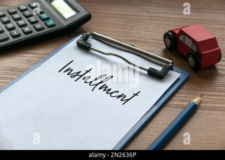 Selective focus of calculator, car toys, pencil, clipboard and paper written with installment on wooden background. Stock Photo