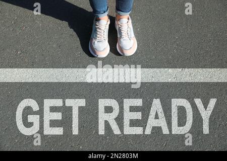 Text Get Ready and line on asphalt in front of woman, closeup view Stock Photo