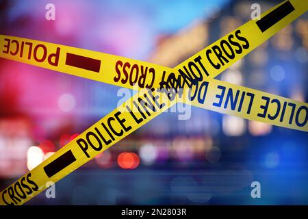 Yellow law enforcement tape isolating crime scene. Blurred view of city, toned in red and blue police car lights Stock Photo