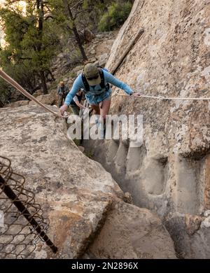 Woman Climbs Up Stone Steps Carved Out of Rock Cliff in Mesa Verde National Park Stock Photo