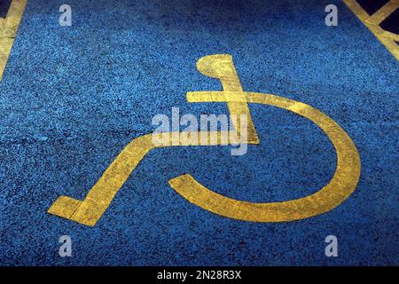 Textured surface on blue and yellow painted,disabled parking space NCP Stockport Stock Photo
