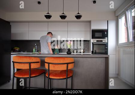Father and son in white and gray modern kitchen interior Stock Photo