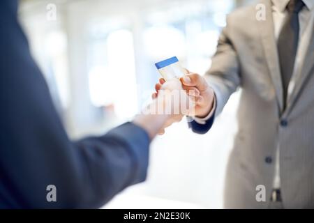 Put it on my business account...Cropped image of a man handing over a credit card to a woman. Stock Photo