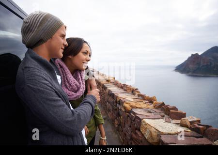 Romance on top of the world. a young couple enjoying the view while out on a drive in the country. Stock Photo