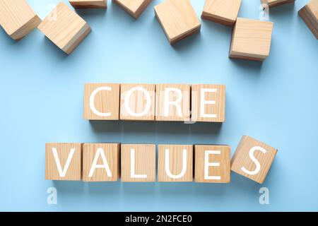 Wooden cubes with phrase CORE VALUES on light blue background, flat lay Stock Photo