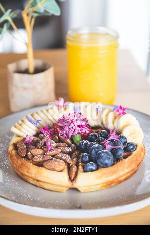 Waffle with almonds, blueberries, strawberries and bananas with honey and a fresh orange juice Stock Photo