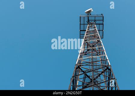 Radio relay antenna on a metal tower. Against the background of the blue sky. Stock Photo