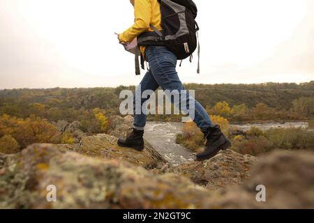 Woman with backpack on steep cliff, closeup Stock Photo