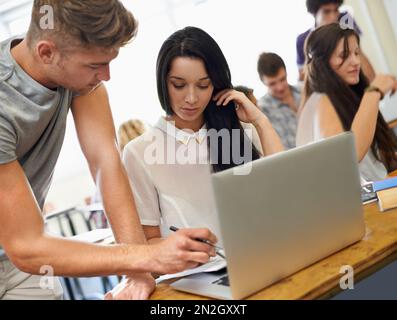 Helping out a classmate. Two students helping each other in a varsity classroom. Stock Photo