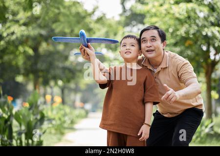 Excited grandfather and grandson playing with toy plane together Stock Photo