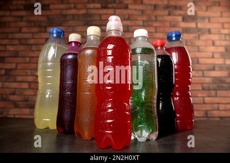 Bottles of soft drinks with water drops on table near brick wall Stock Photo