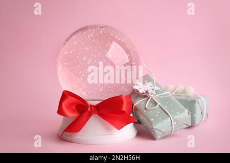 Beautiful empty snow globe and gift boxes on pink background Stock Photo