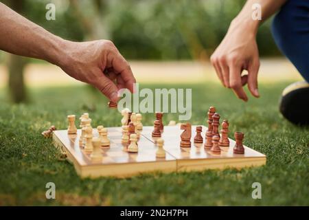 Closeup image of senior father and adult son playing chess outdoors Stock Photo