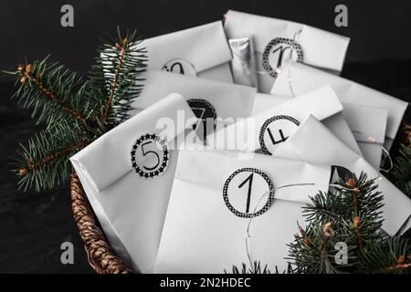 Paper bags, fir branches and garland in wicker basket, closeup. Christmas advent calendar Stock Photo