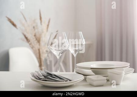 Set of clean dishware, wineglasses and cutlery on white table indoors Stock Photo