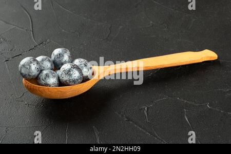 Wooden spoon with sweets hazelnuts in chocolate close-up on a dark background. Stock Photo