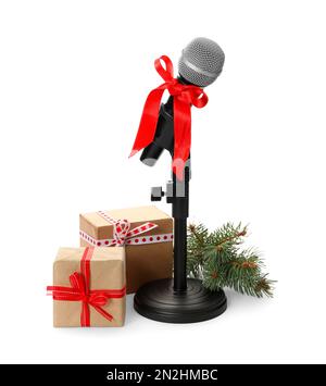 Microphone with red bow, gift boxes and festive decor on white background. Christmas music Stock Photo