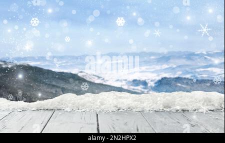 Wooden board with snow and blurred mountains on background. Christmas time Stock Photo