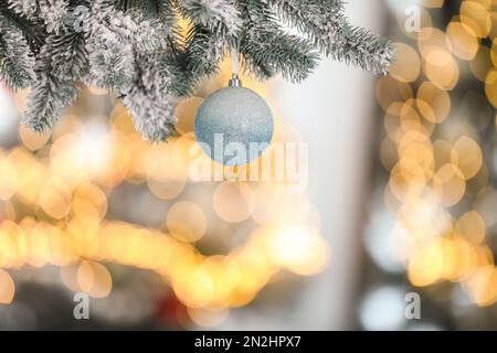 Beautiful holiday bauble hanging on Christmas tree against blurred fairy lights, closeup Stock Photo