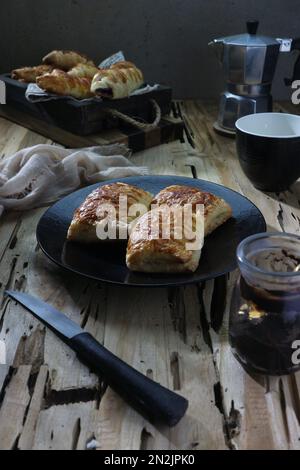 Baked cheesecake on a plate against a background of piles of bread on a wooden tray Stock Photo