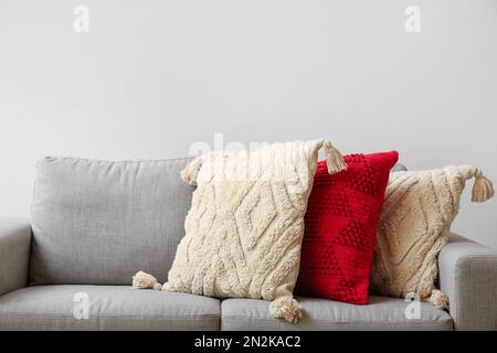 Decorative pillows on sofa near light wall, closeup Stock Photo