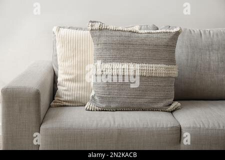 Decorative pillows on sofa near light wall, closeup Stock Photo