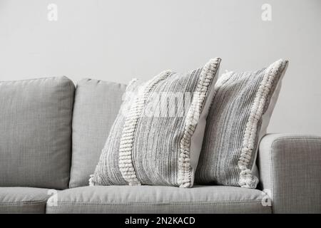 Soft pillows on sofa near light wall, closeup Stock Photo
