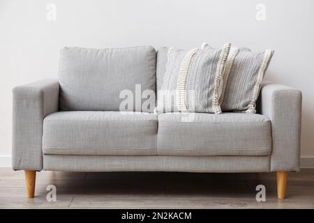 Soft pillows on sofa near light wall Stock Photo