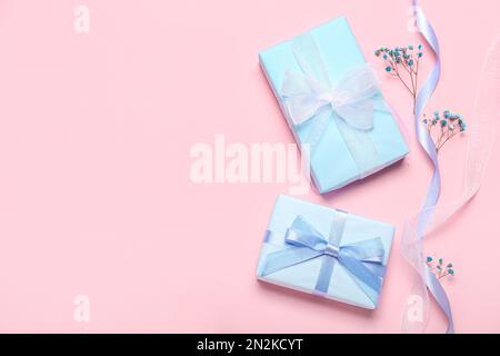 Composition with gift boxes, ribbon and gypsophila flowers on pink background. Women's Day celebration Stock Photo