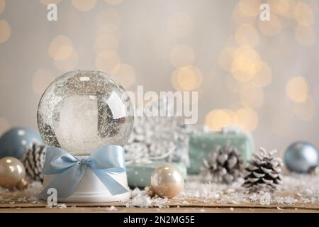 Beautiful empty snow globe and Christmas decor on table against blurred festive lights. Space for text Stock Photo