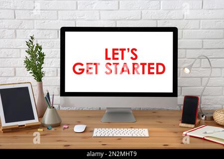 Modern computer monitor with phrase Let's Get started on screen in office Stock Photo