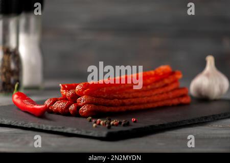 Delicious dried sausages Kabanosy with spices and herbs. Side view. Free space for text. Stock Photo