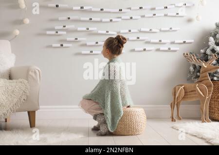 Little girl sitting near New Year advent calendar at home Stock Photo