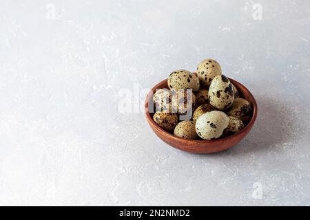 quail eggs in wooden bowl on grey concrete background, copy space, minimalism, Easter concept Stock Photo