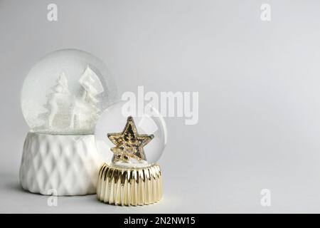 Beautiful snow globes on light grey background, space for text Stock Photo