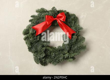 Christmas wreath made of fir tree branches with red ribbon on light grey marble background Stock Photo