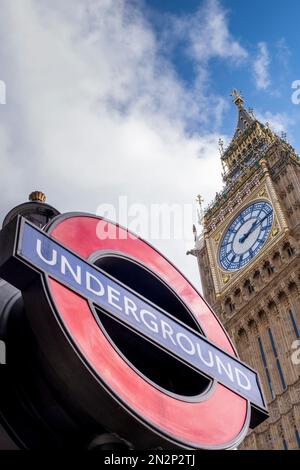 London, Westminster. Big Ben tower at the Houses of Parliament & the Subway (Metro/Underground/Tube) sign at Westminster station. Public transport. Stock Photo