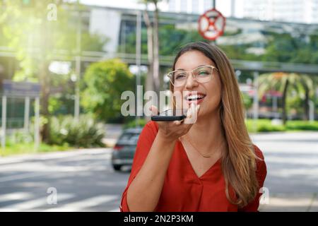 Brazilian girl smiling happy sending voice message using smartphone in Morumbi district of Sao Paulo, Brazil Stock Photo