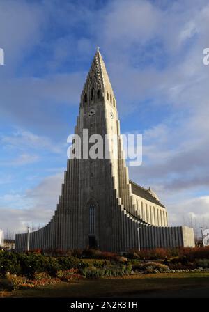 A vertical shot of Hallgrimskirkja Lutheran church in Reykjavik around green plants, Iceland Stock Photo