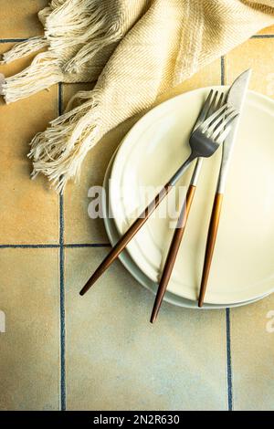 Overhead view of plates and cutlery on a  table next to a tiled table runner Stock Photo