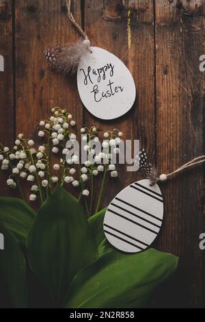 Overhead view of lily of the valley flowers on a wooden table with Happy Easter gift tags Stock Photo