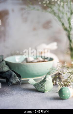 Close-up of an Easter Place setting with Easter eggs in a bowl, ornaments and white Gypsophila flowers Stock Photo
