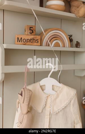 Close-up of child's clothing hanging on a coathanger with children's toys on shelves Stock Photo