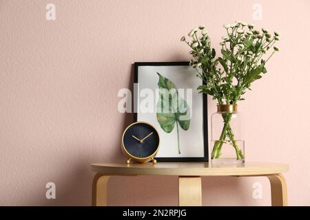 Composition with chrysanthemum flowers in glass vase on wooden table near pink wall. Space for text Stock Photo