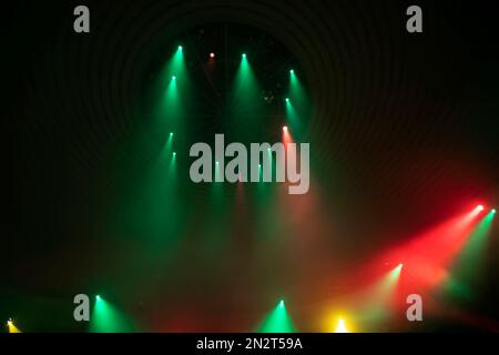 Green and red rays from stage spotlights on a dark background. Stock Photo