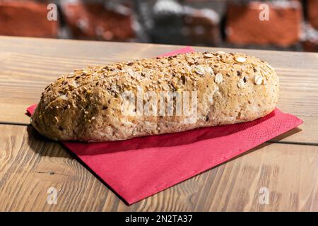 From above of loaf of fresh bread with grains placed on paper napkin on table in restaurant Stock Photo