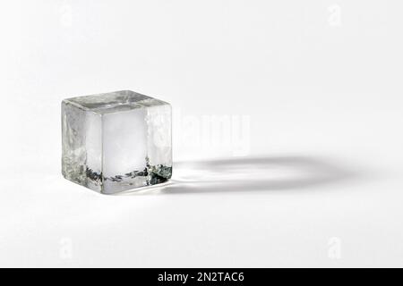 Clean crystal cube made of transparent fragile glass casting shadow on gray background Stock Photo