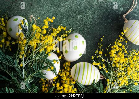 Overhead view of painted Easter eggs with yellow mimosa flowers on a table Stock Photo