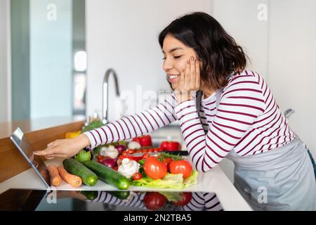 Smiling beautiful young woman chef cooking at home Stock Photo
